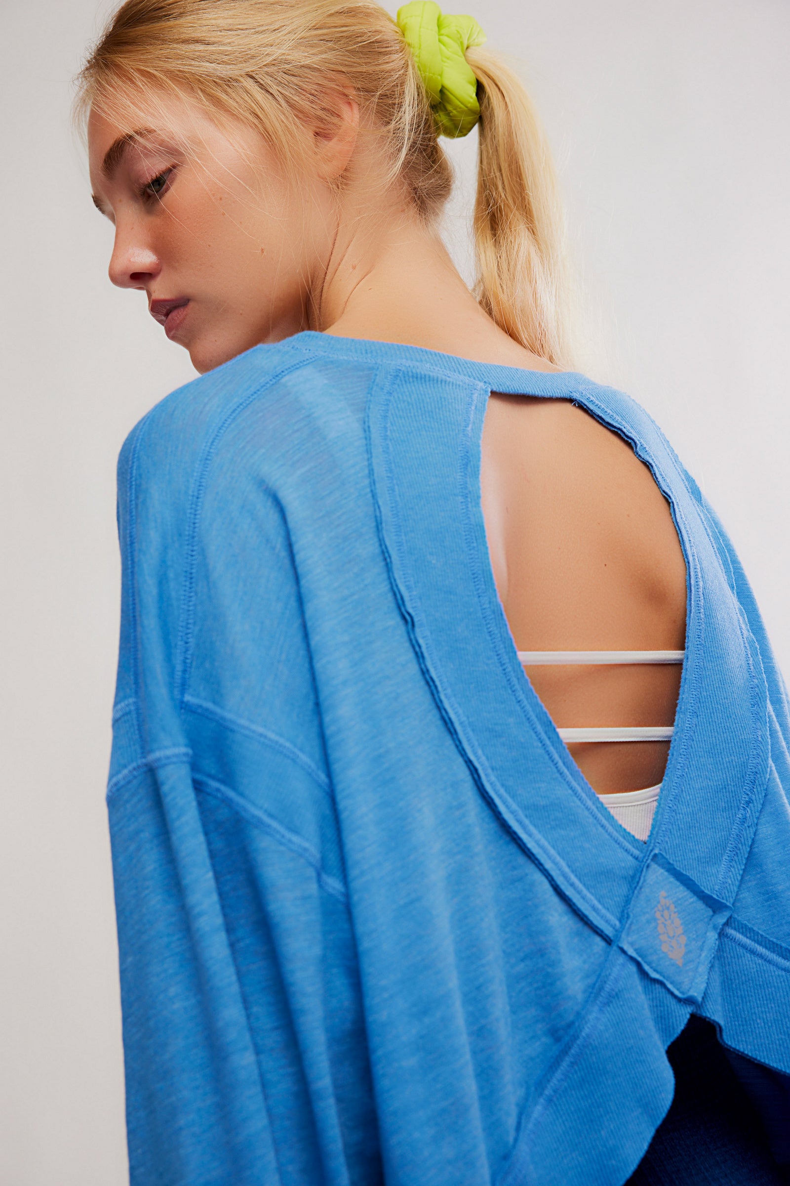 Woman wearing a blue open-back top with a plain background