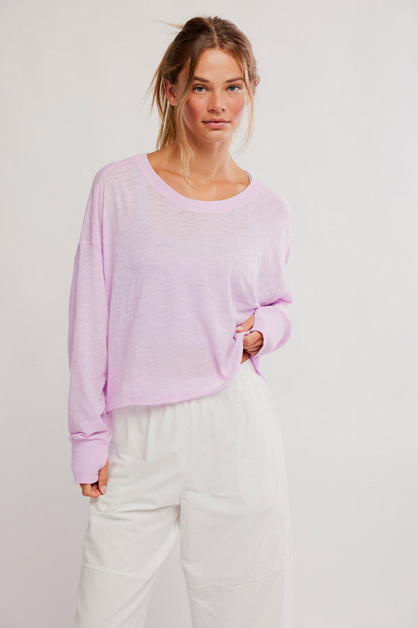 Woman wearing a light purple sweater and white pants on a plain background