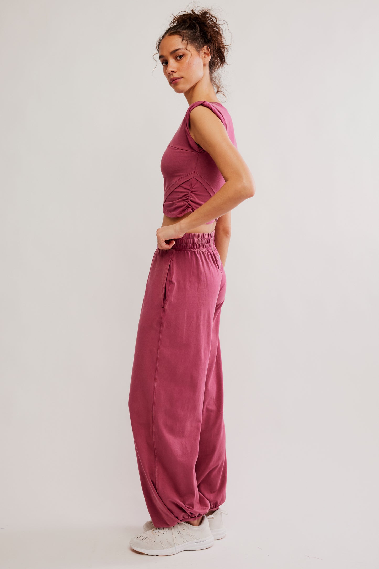 Woman wearing a pink outfit with wide-leg pants on a light background