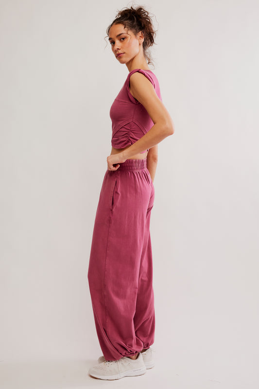 Woman wearing a pink outfit with wide-leg pants on a light background