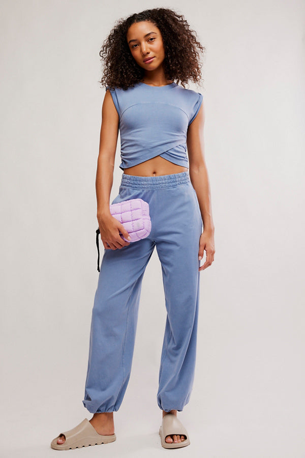 Woman wearing a blue outfit with a pink pouch against a plain background