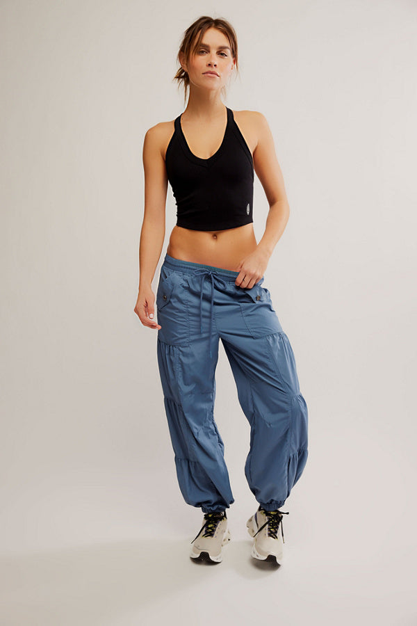 Woman wearing a black sports bra and blue pants on a plain background