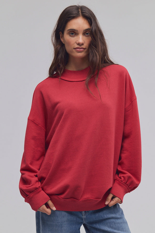 Person wearing a red sweatshirt and blue jeans on a gray background