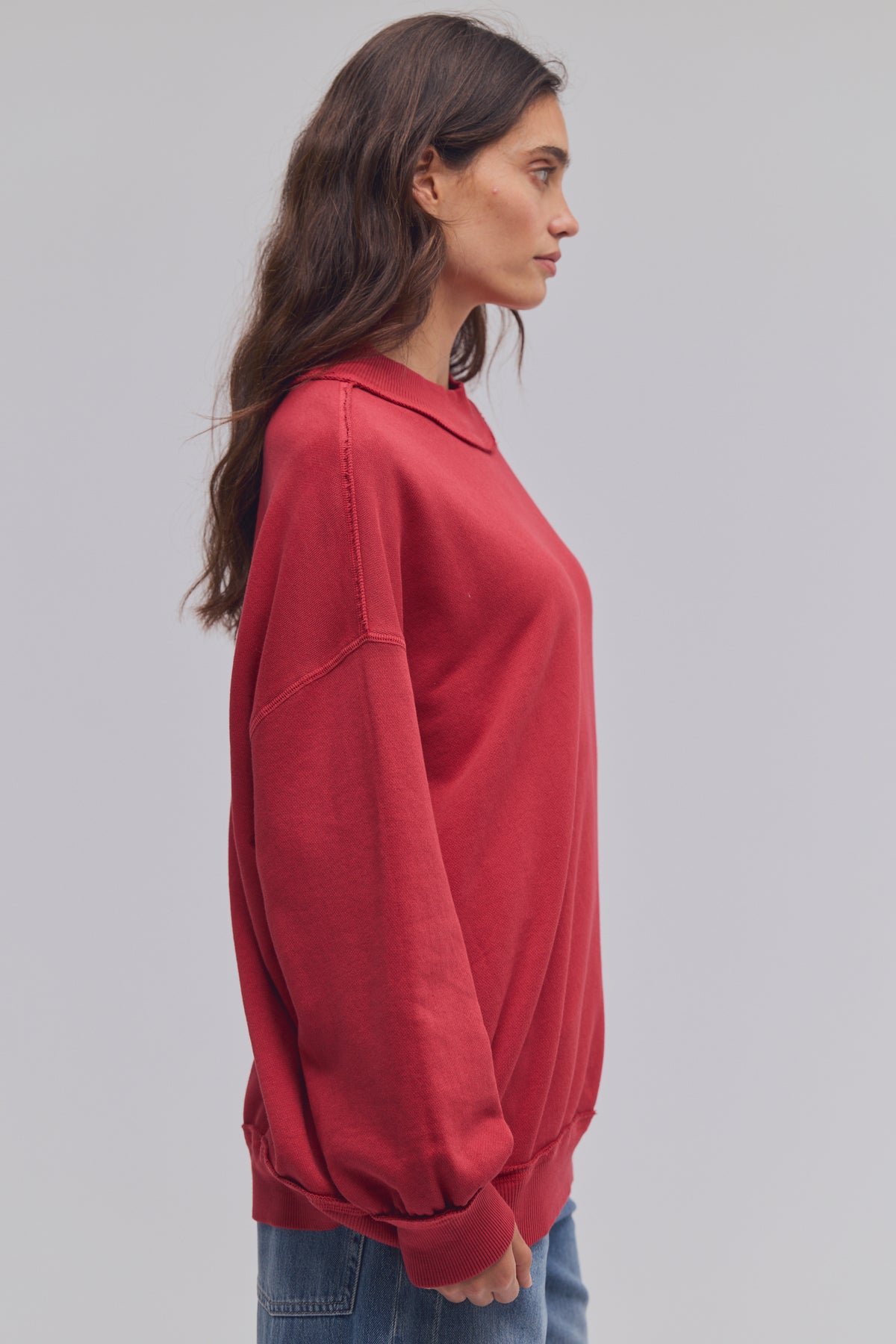 Woman wearing a red sweatshirt against a gray background