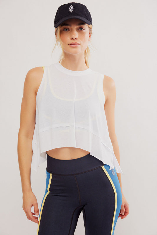 Woman wearing a white sleeveless top and black leggings with yellow accents on a plain background