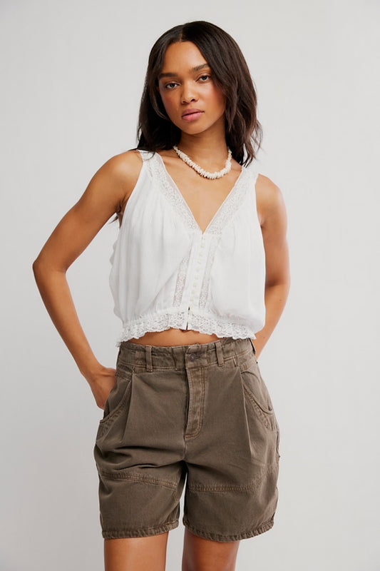 Woman wearing a white top and brown shorts against a plain background