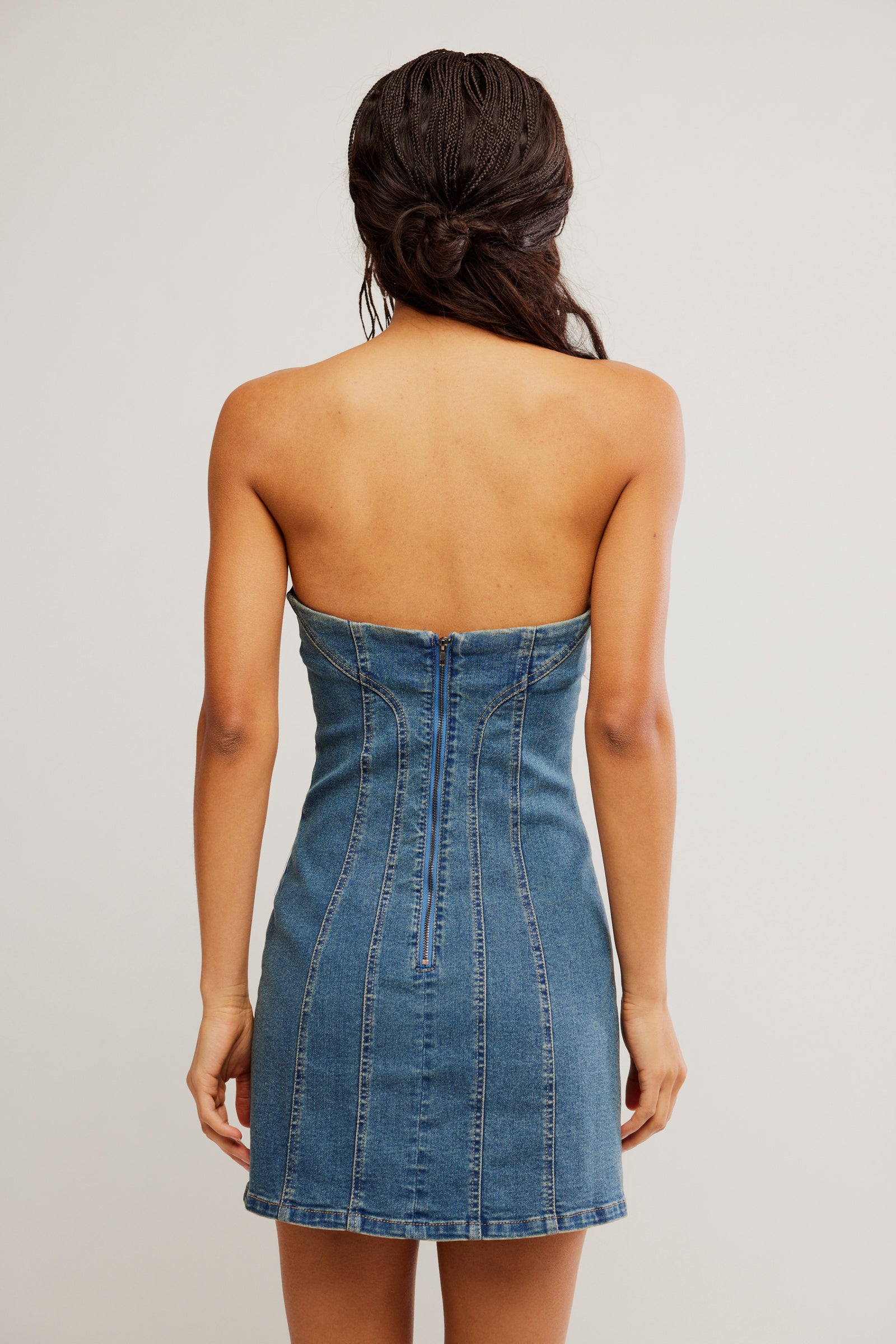 Woman wearing a strapless denim dress against a plain background