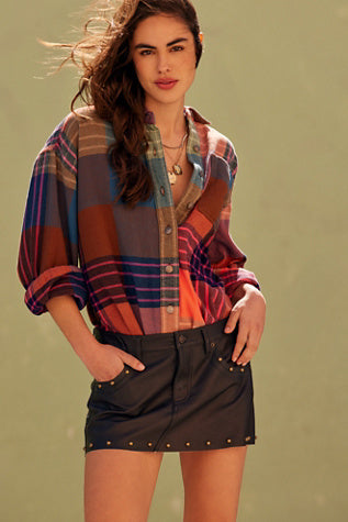 Woman wearing a plaid shirt and black skirt against a green background