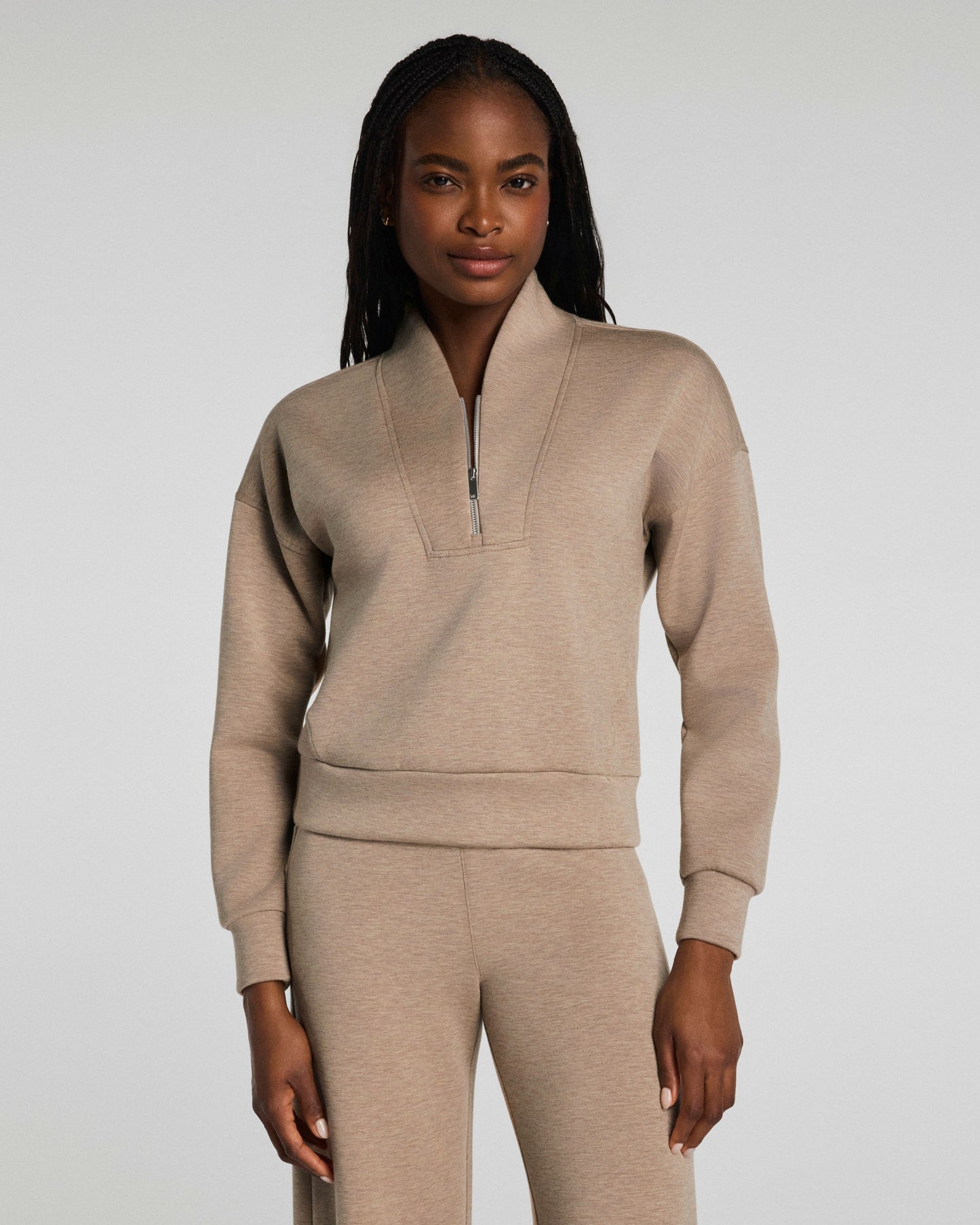 Woman wearing a Spanx beige tracksuit against a plain background