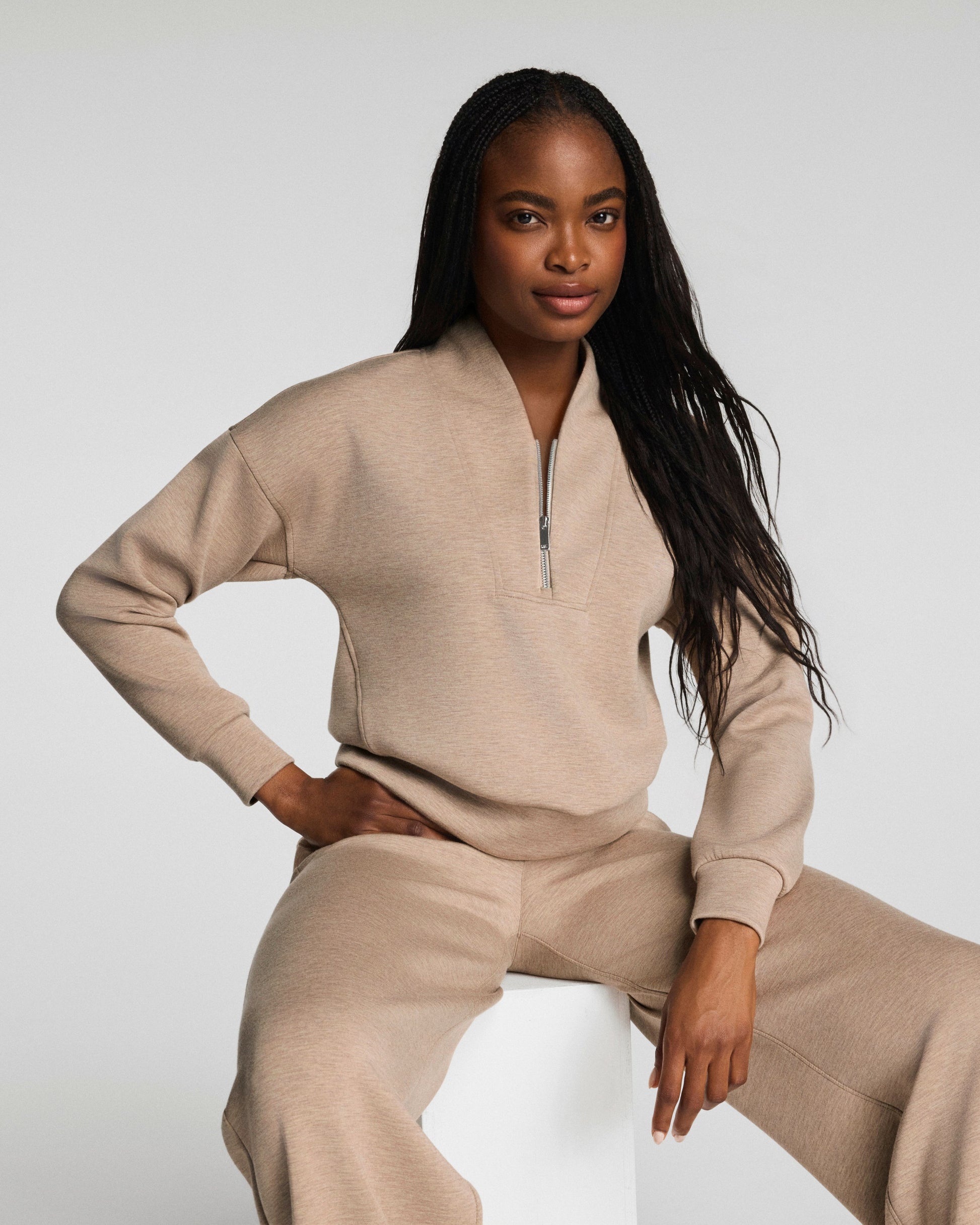 Woman wearing a Spanx beige loungewear set on a white background