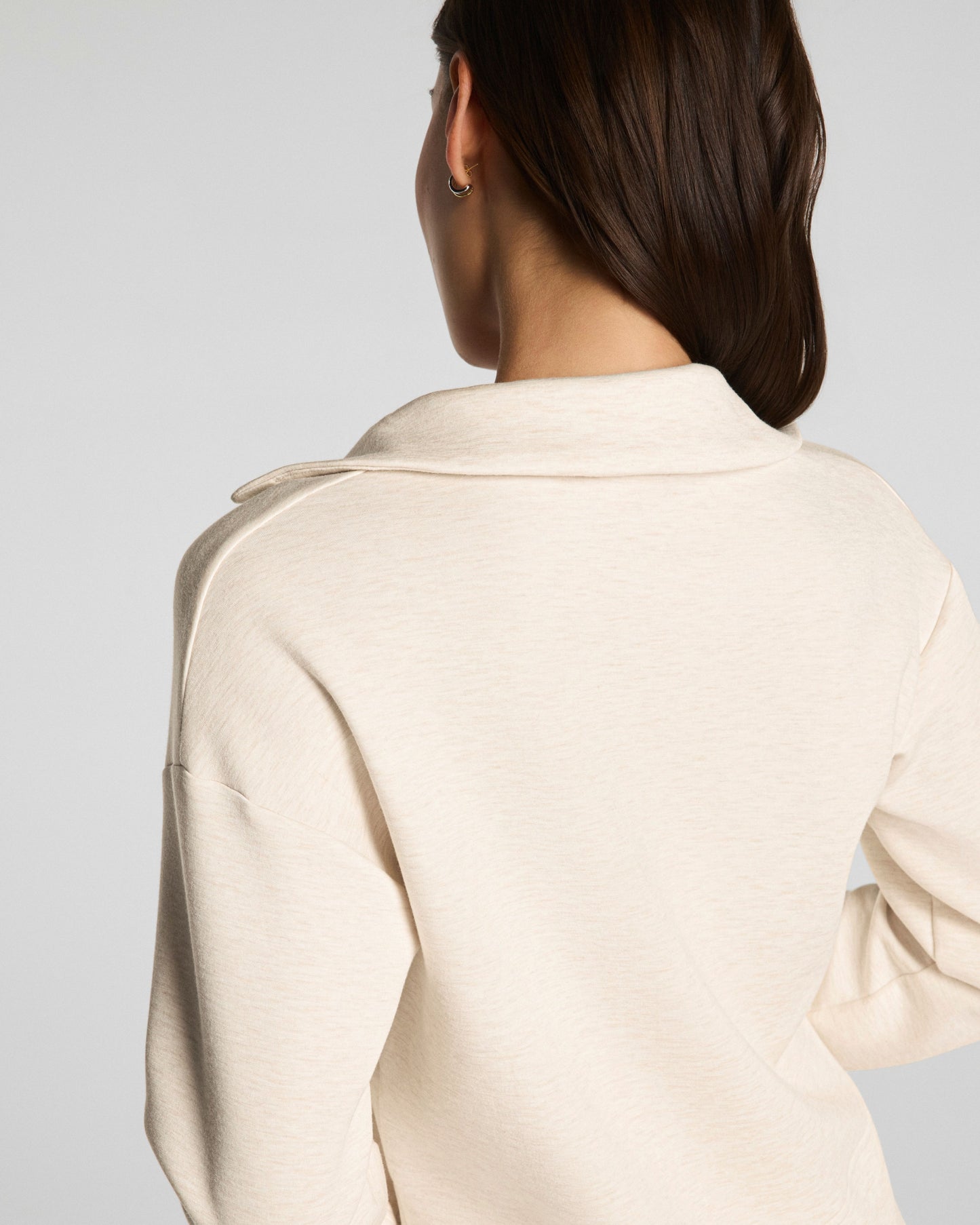 Person wearing a SPANX beige coat on a plain background