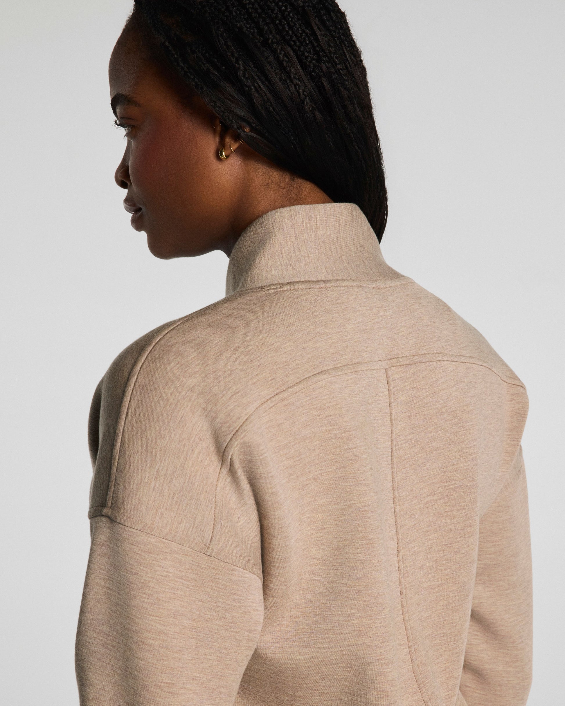 Person wearing a Spanx beige jacket on a plain background