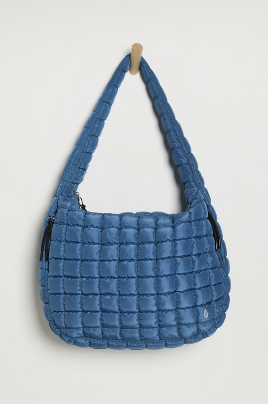 Blue quilted handbag on a light gray background