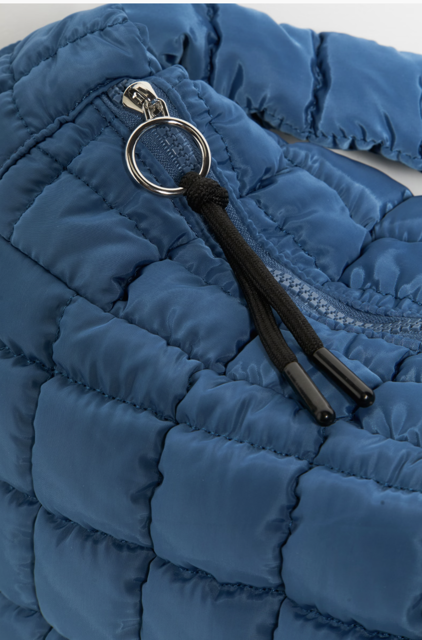 Close-up of a blue quilted puffer jacket with a silver metal ring and black drawstring zipper pull.
