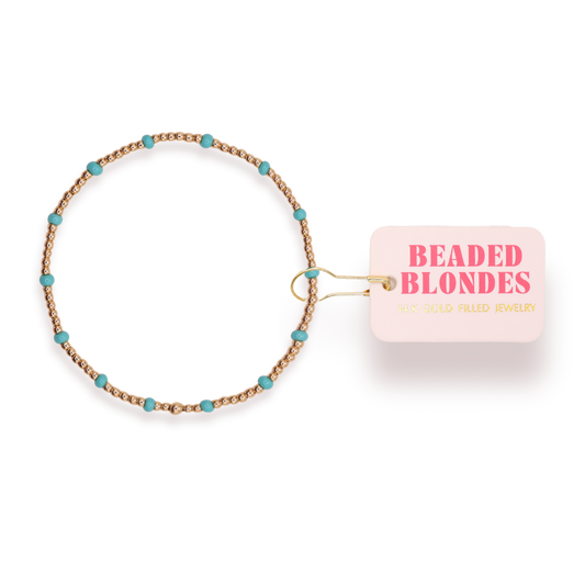 Beaded hair tie with turquoise beads and a pink card labeled 'Beaded Blondes' on a white background