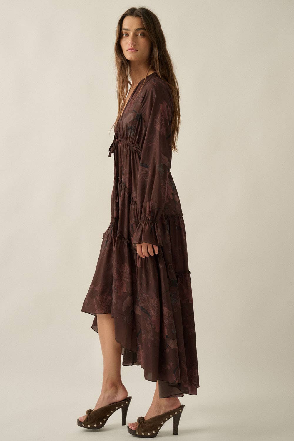 Woman wearing a brown patterned dress against a plain background