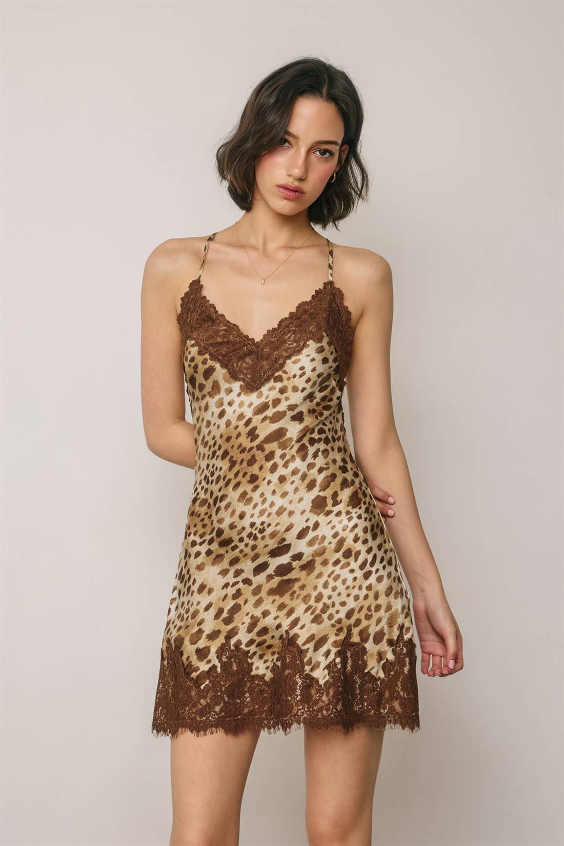 Woman wearing a leopard print lace slip dress against a plain background