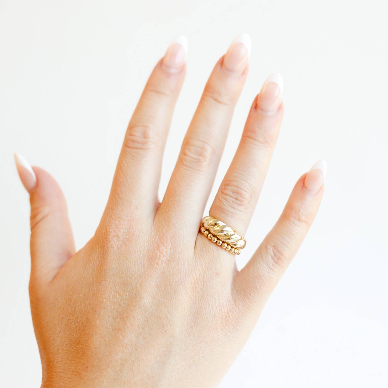 Hand wearing a gold ring on a white background