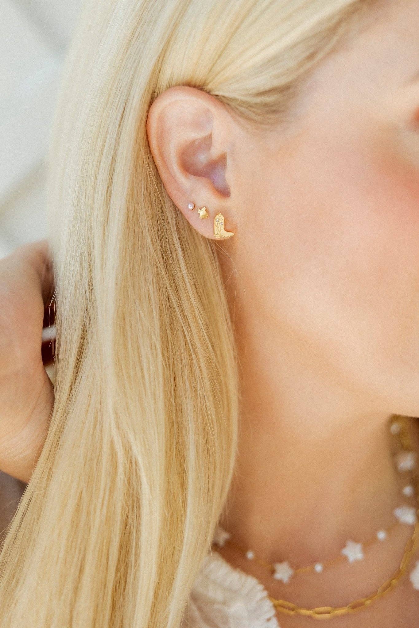 Close-up of a person wearing gold earrings with star designs.