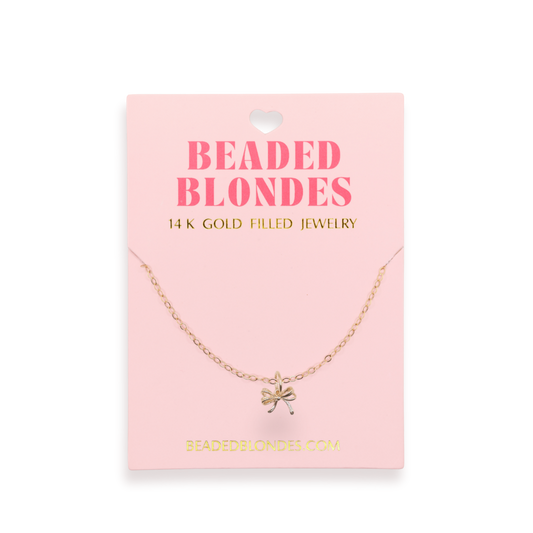 Gold necklace on a pink card with 'Beaded Blondes' branding