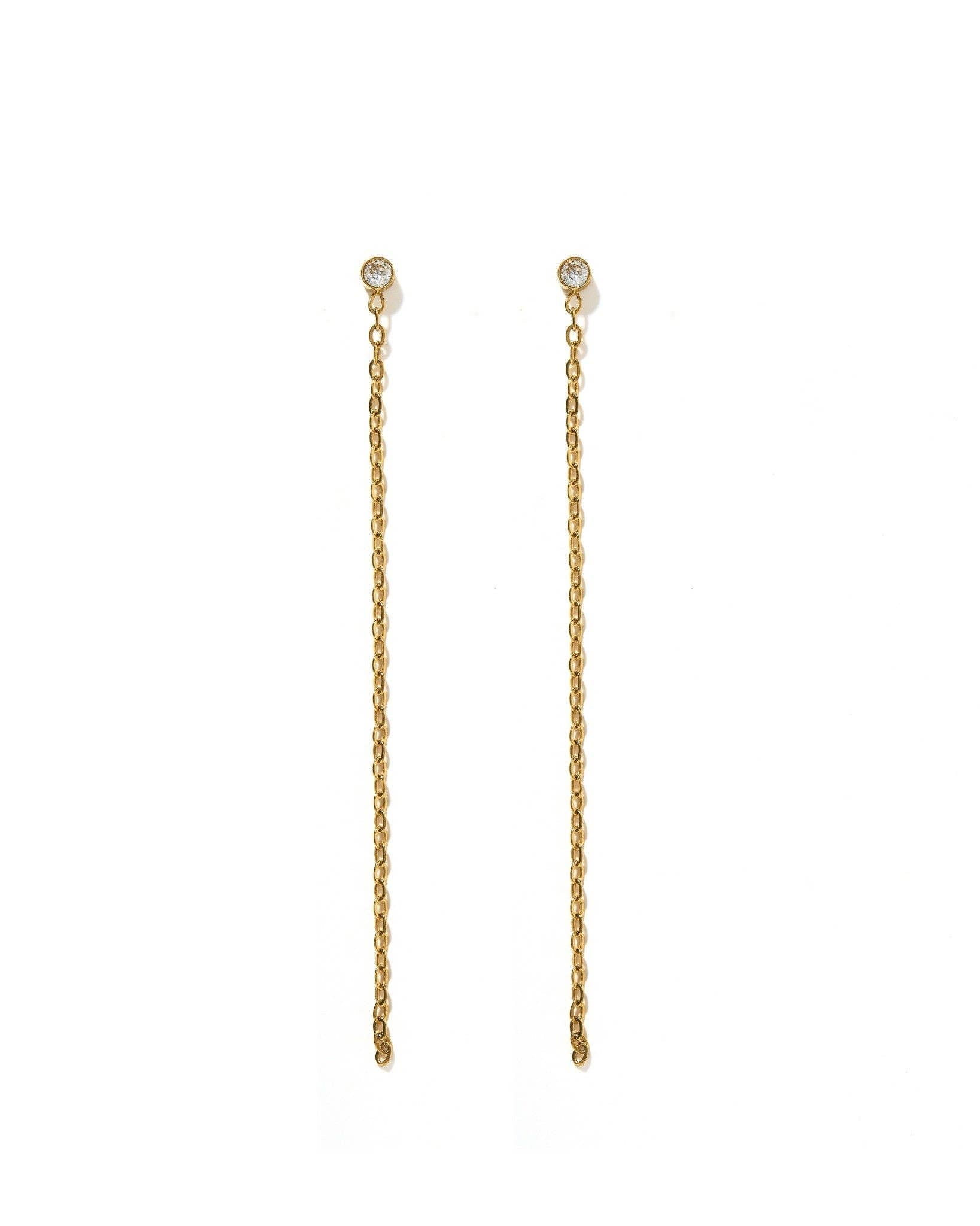 A pair of gold drop earrings with a small round clear stone at the top and a long, delicate chain dangle below, shown on a plain white background.