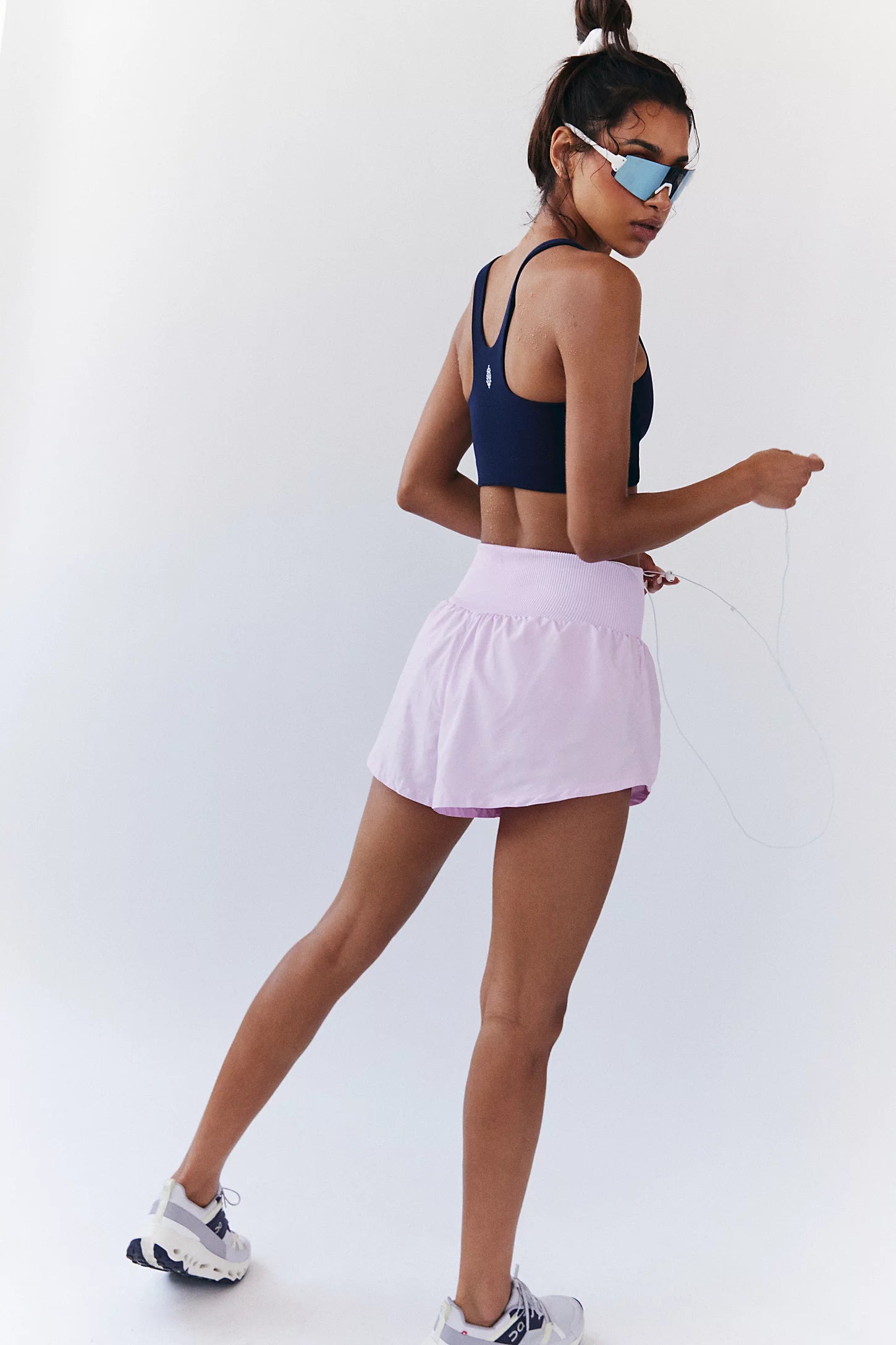 Woman wearing a navy sports bra and pink shorts on a white background