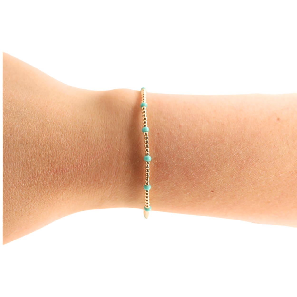 Gold and turquoise beaded bracelet on a wrist against a white background