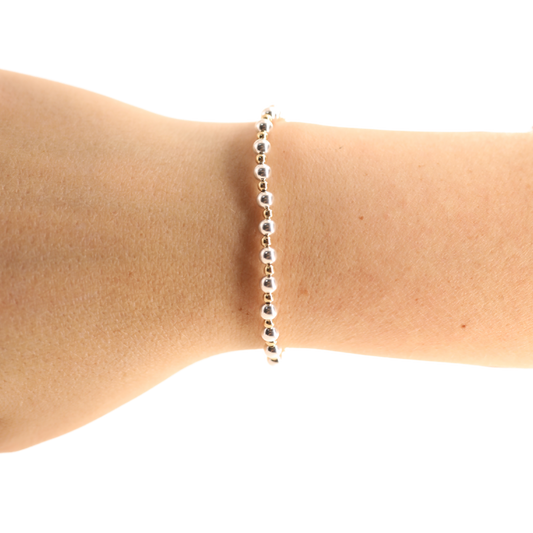 Silver beaded bracelet on a person's wrist against a white background