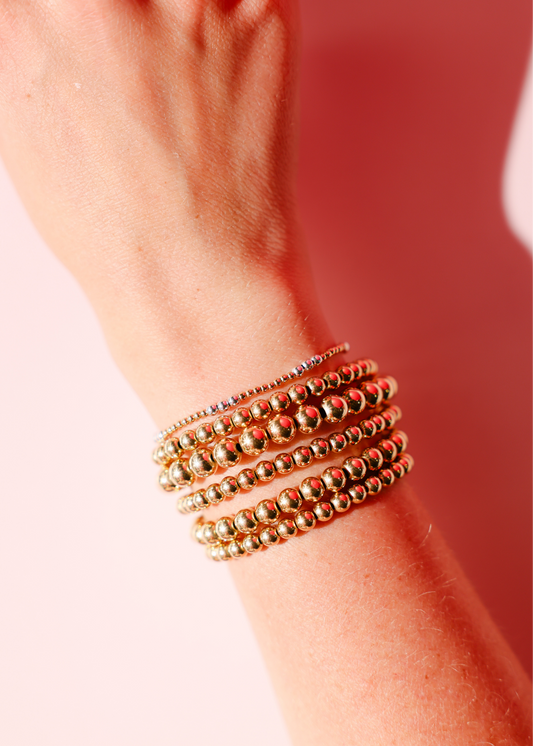 Gold bracelets on a wrist with a blurred background