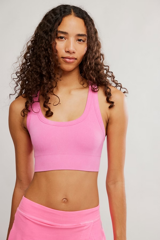 Woman wearing a pink sports bra and skirt on a plain background