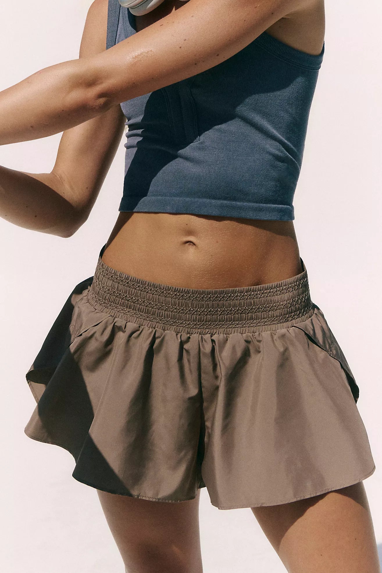 Woman wearing Free People Element Shorts in Sandstorm with white background. 