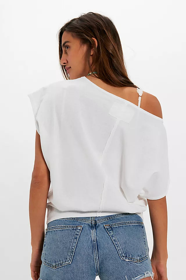 Woman wearing a white one-shoulder top and blue jeans on a white background
