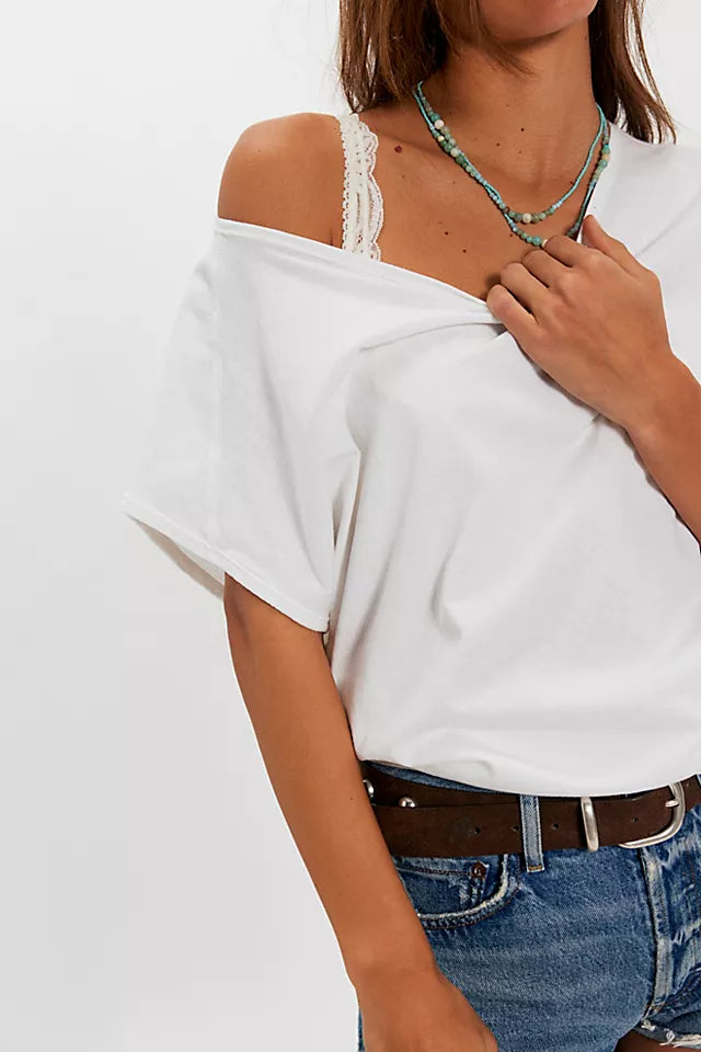 Person wearing a white off-shoulder top and blue jeans on a plain background