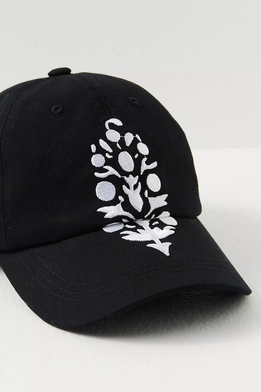 Black cap with white floral design on a light gray background
