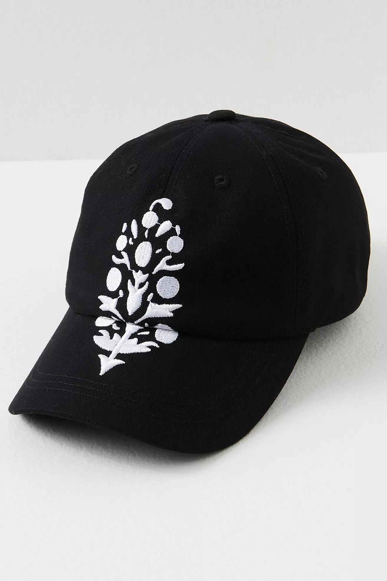 Black cap with white floral design on a white background