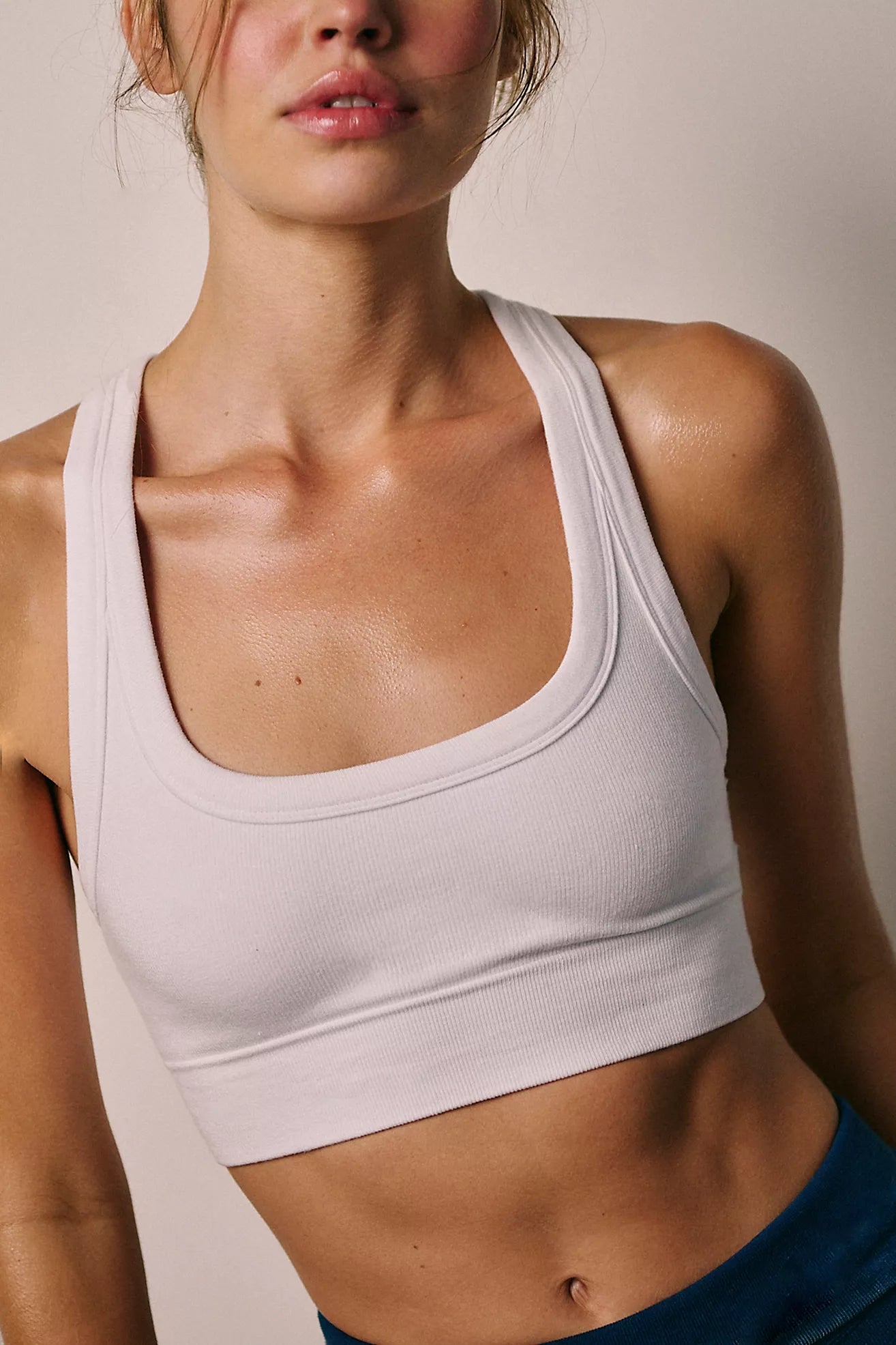 Woman wearing a white sports bra against a neutral background