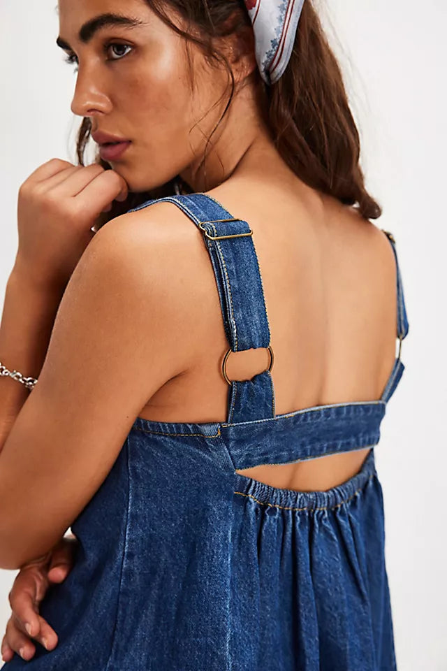 Woman wearing a blue denim dress with cut-out design on a white background