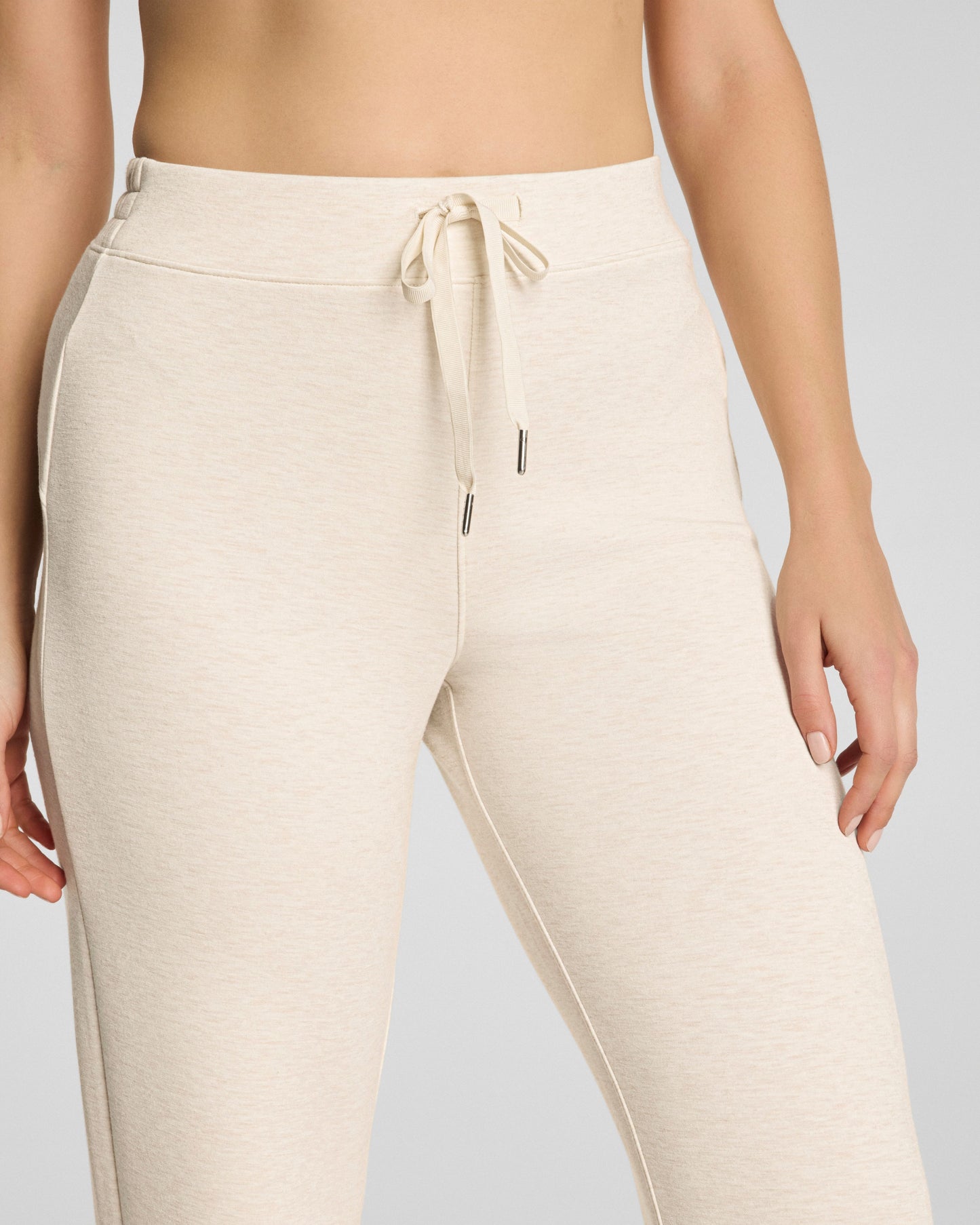 Beige jogger pants with drawstring on a plain background