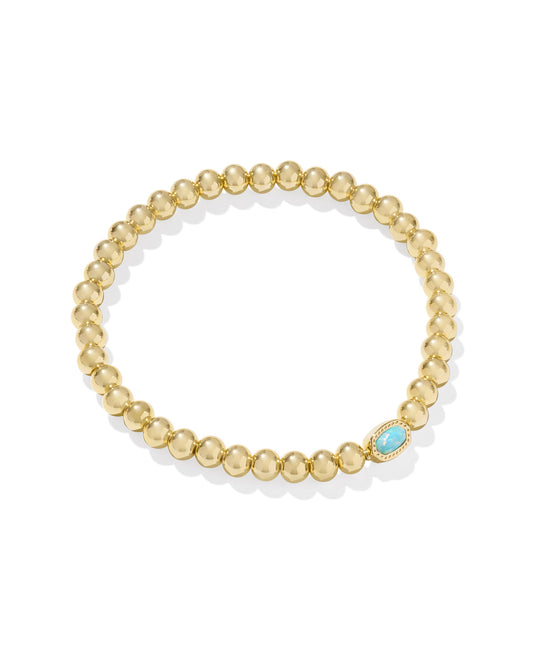 Gold beaded bracelet with a blue gemstone on a white background