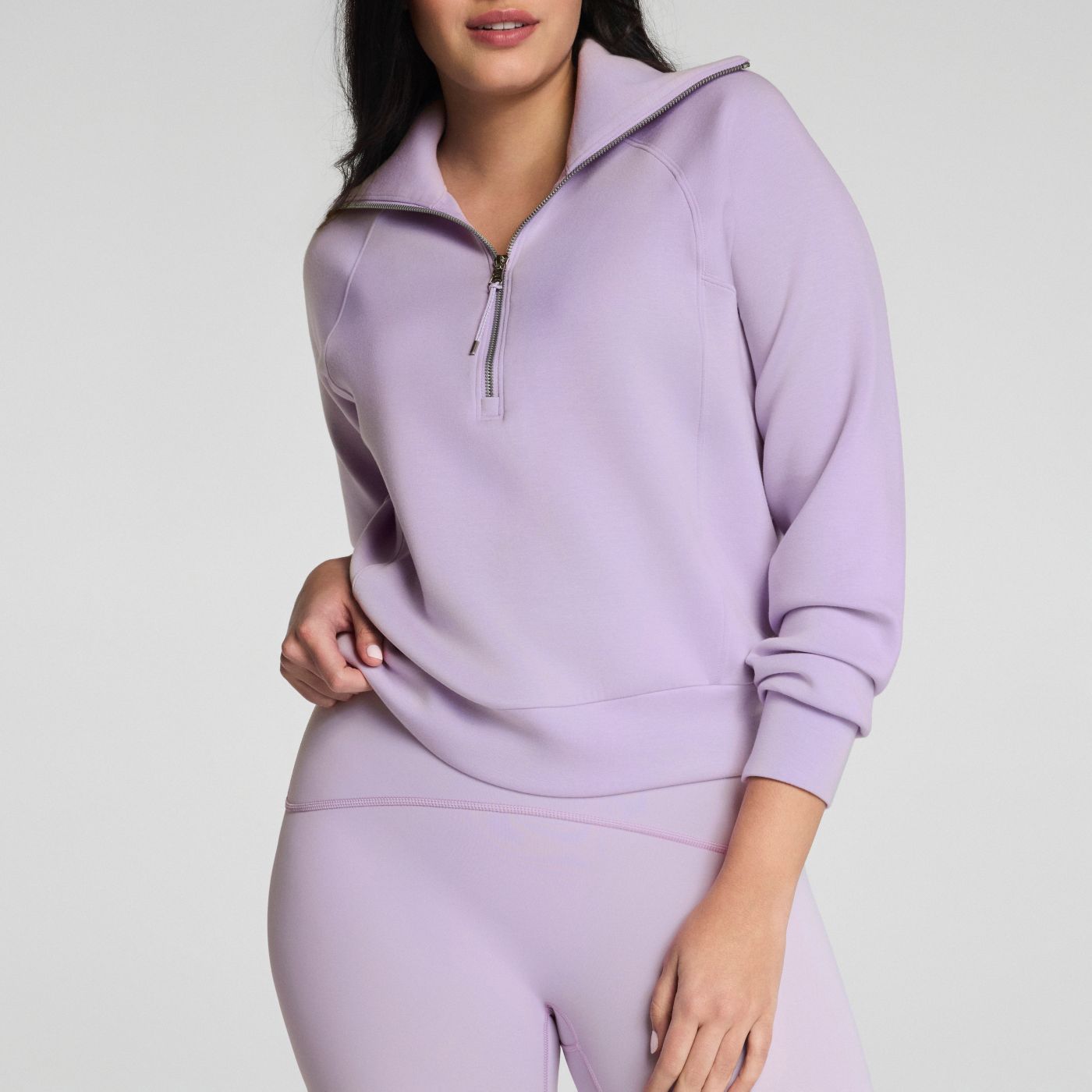 Person wearing a lavender hoodie and leggings set on a light gray background