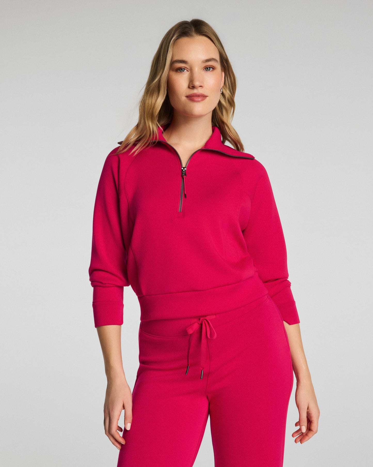Woman wearing a pink tracksuit on a gray background