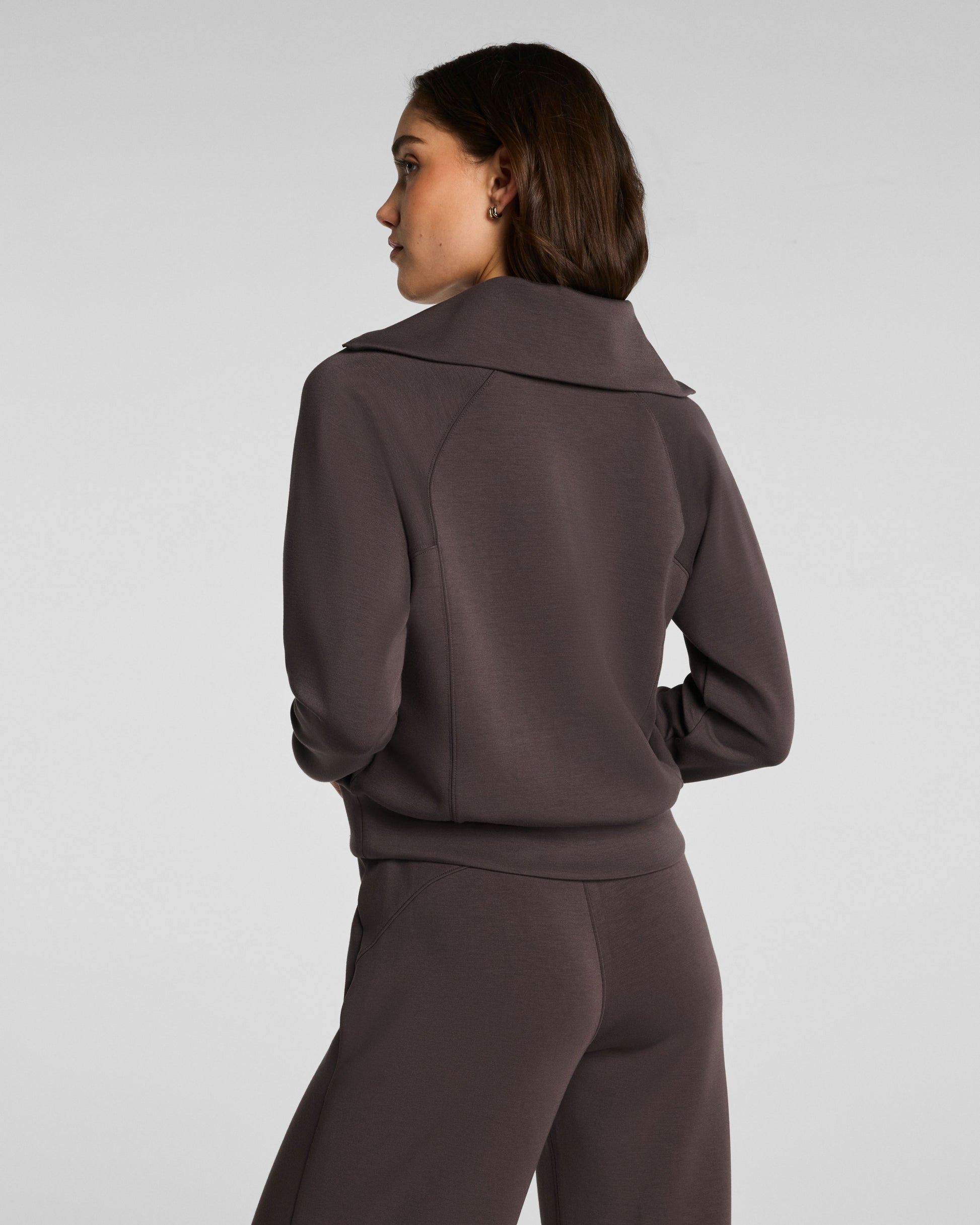 Person wearing a brown tracksuit against a light gray background